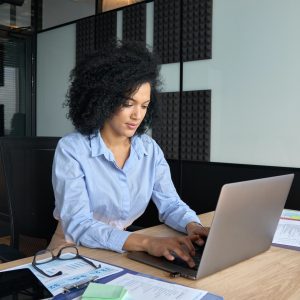 Concentrated African American businesswoman working typing using pc laptop.