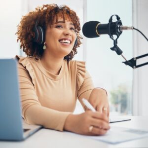 Laptop, microphone and radio with a black woman presenter talking during a broadcast while live str