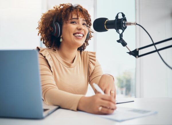 Laptop, microphone and radio with a black woman presenter talking during a broadcast while live str