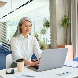 Smiling mid age businesswoman financial manager working typing using pc laptop.