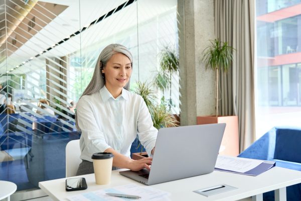 Smiling mid age businesswoman financial manager working typing using pc laptop.