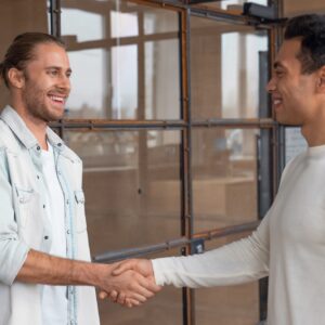 Young businessman shaking hands with male colleague after meeting in boardroom