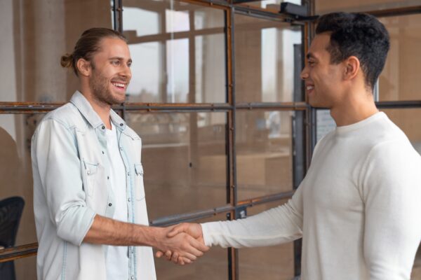 Young businessman shaking hands with male colleague after meeting in boardroom